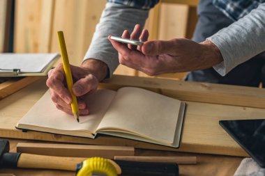 Marangoz smartphone kullanırken project notları yazma