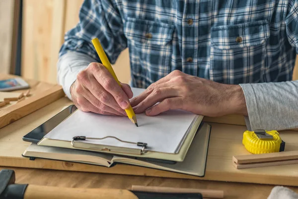 Carpintero escribir notas del proyecto portapapeles y hacer lista — Foto de Stock