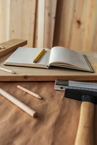 Cuaderno de notas y herramientas sobre el escritorio del taller de carpintería — Foto de Stock