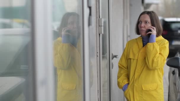 Mujer Con Impermeable Amarillo Hablando Por Teléfono Móvil Incredulidad Calle — Vídeos de Stock