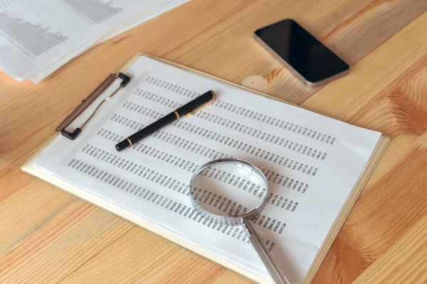 Business report analysis, magnifying glass over paper spreadshee — Stock Photo, Image