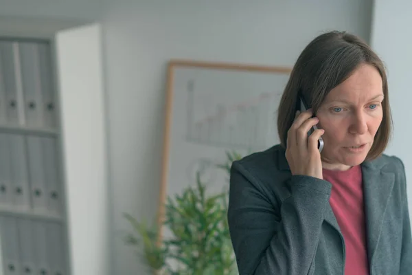 Zakenvrouw in mobiele telefoongesprek door het loket — Stockfoto