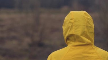 Bulutlu yağmurlu kış gününde, ağır çekim el görüntüleri mesafe içine bakarak yağmurluk içinde kadın arkadan görünüş