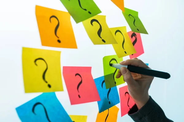 Empresária escrevendo pontos de interrogação sobre colorida nota pegajosa pap — Fotografia de Stock