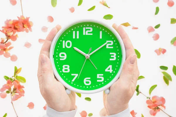 Female hands holding alarm clock with colorful springtime decora — Stock Photo, Image