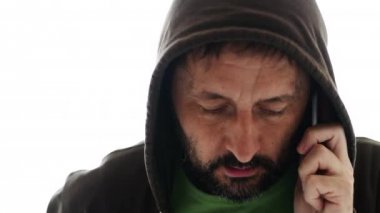 Cep telefonu, beyaz arka plan üzerinde izole konuşmak hoodie ile gergin adam