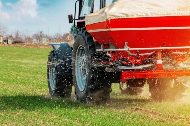 Agricultural tractor fertilizing wheat crop field with NPK clipart