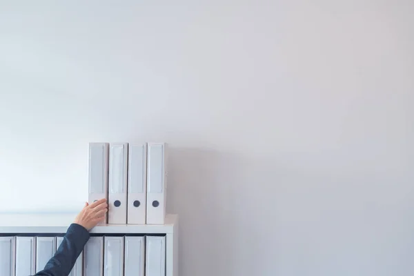 Hand greift nach Aktenordner im Büroregal — Stockfoto