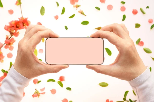 Mobile phone mock up in female hand with springtime decoration