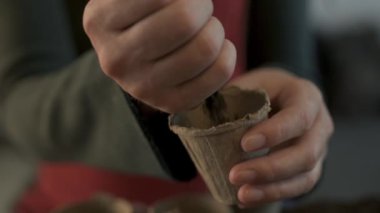 Bahçıvan organik gıda üretim bahçesinde tohum Ekim ve dikim için hazır biyolojik toprak turba pot konteyner dolum, kadın elleri yakın