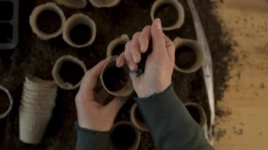 Bahçıvan organik gıda üretim bahçesinde tohum Ekim ve dikim için hazır biyolojik toprak turba pot konteyner dolum, kadın elleri yakın