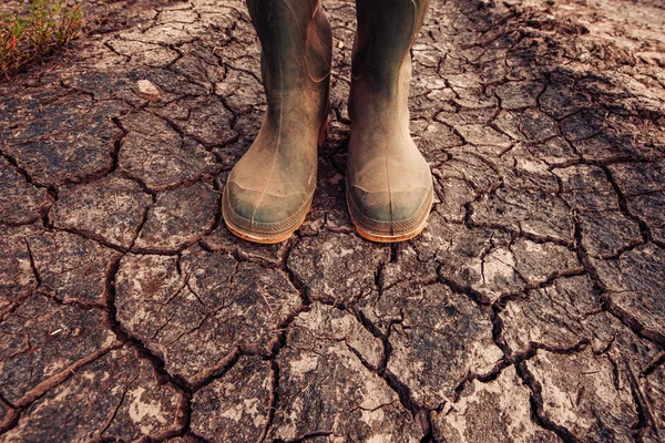 Farmer in rubber boots standing on dry soil ground — Stock Photo, Image