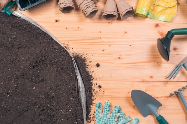 Gardening tools on potting soil, top view