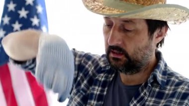 Amerikalı çiftçi onun vlog için turba pot gözden, arka planda Abd bayrağı ile hasır şapka ve ekose gömlek ile yetişkin erkek kişinin headshot