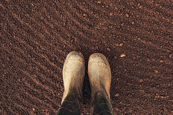 Vue du dessus des bottes en caoutchouc des agriculteurs sur les terres labourées — Photo