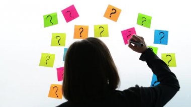 Soru işaretleri office beyaz tahta, seçici odak renkli yapışkan not kağıdına yazılı iş kadını
