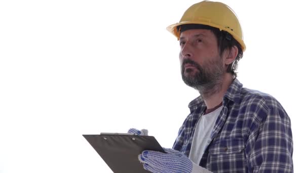 建筑工人在剪贴板记事本纸上书写项目笔记 在白色背景上隔离 戴着黄色防护头盔 — 图库视频影像
