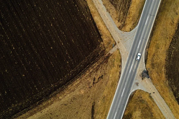 Вид з повітря на одиночний білий автомобіль на дорозі через сільську місцевість — стокове фото