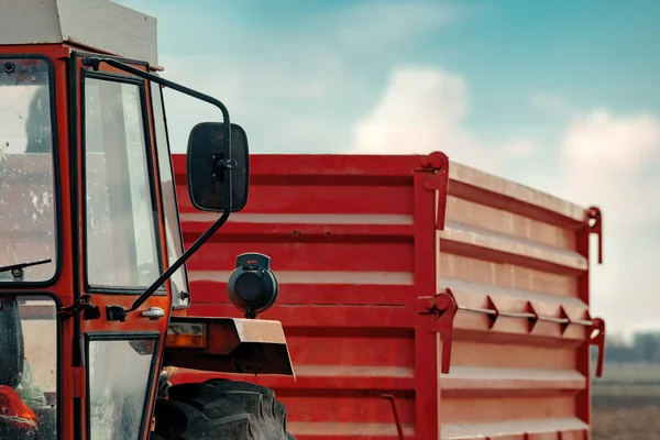 Vecchio trattore agricolo rosso con rimorchio sulla campagna sporca ro — Foto Stock