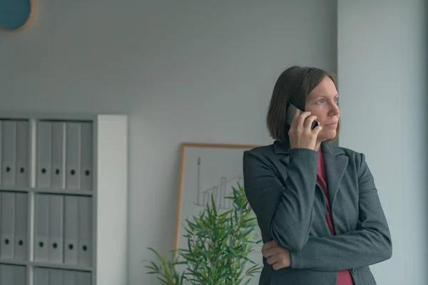 Donna d'affari seria che parla al cellulare in ufficio — Foto Stock