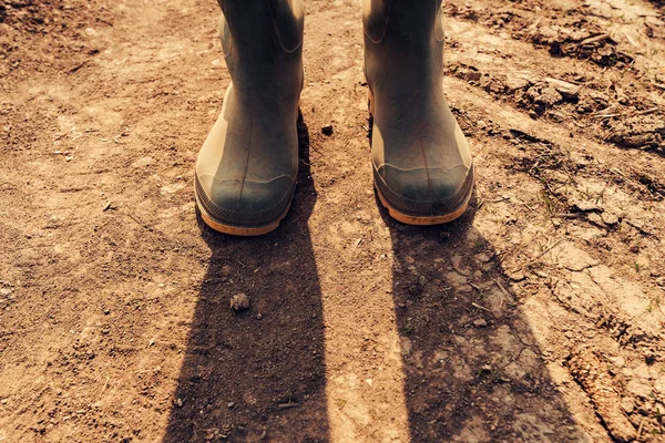Agricultor em pé na estrada de terra, perto de botas — Fotografia de Stock