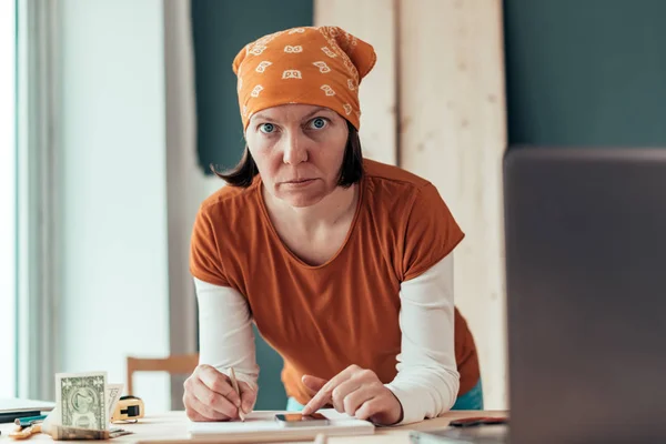 Female carpenter doing financial calculation — Stock Photo, Image