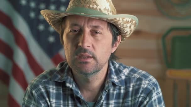 アメリカの牧場主は 彼の農業活動についてVlogを作り チェック柄のシャツと麦わら帽子を持つ成人男性がカメラを見て話しています — ストック動画