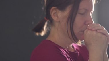 Karanlık odada elleri sımsıkı bağlı dua eden kadın, el kamerası görüntüleri.