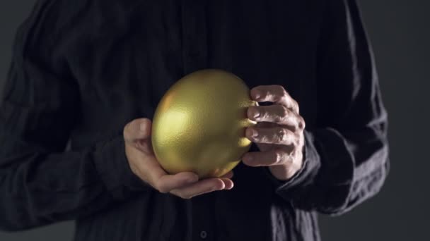 Hombre Sosteniendo Huevo Dorado Primer Plano Persona Masculina Interior Oscuro — Vídeos de Stock