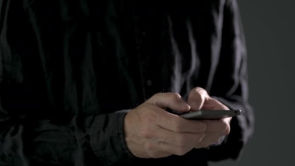 暗い部屋でスマートフォンにテキストメッセージを入力する男性の手のクローズアップ — ストック動画