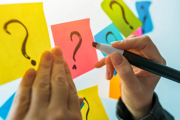 Mujer de negocios escribiendo signos de interrogación en la nota pegajosa colorido pap — Foto de Stock