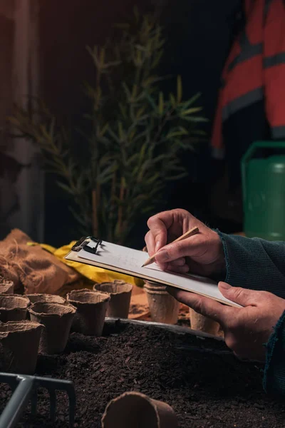 Gärtner schreibt Notizen auf Klemmbrettpapier — Stockfoto