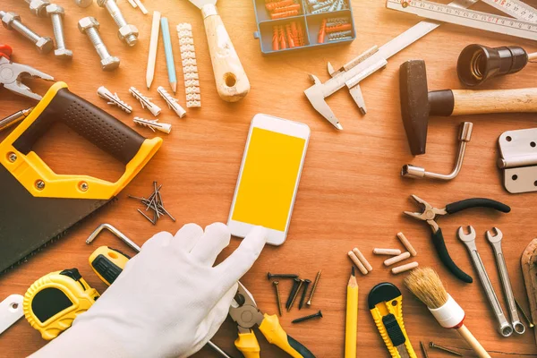 Flatlay handyman aplicativo smartphone, reparador segurando telefone celular — Fotografia de Stock