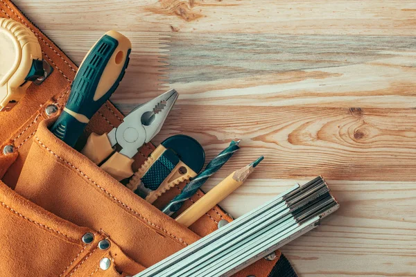 Carpentry tool belt on woodwork workshop desk, top view — Stock Photo, Image