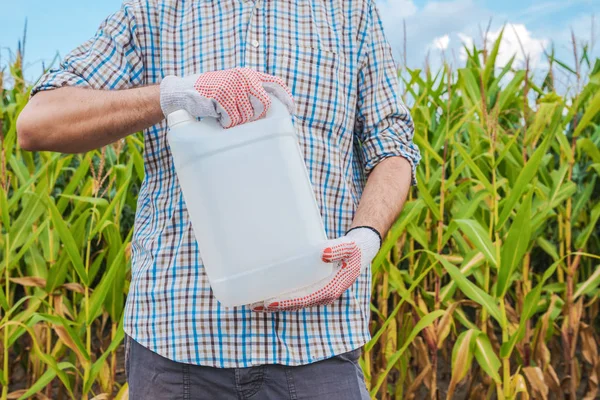 Landwirt hält unetikettierten Pestizidkrug auf Feld — Stockfoto