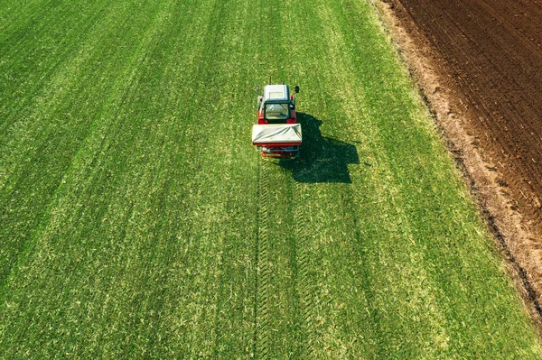 Agricultural tractor fertilizing wheat crop field with NPK — Stock Photo, Image