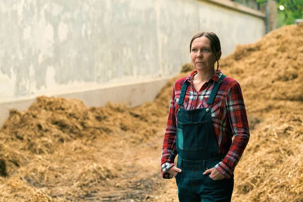 Ženská farmářka stojící před hromadou hnoje — Stock fotografie