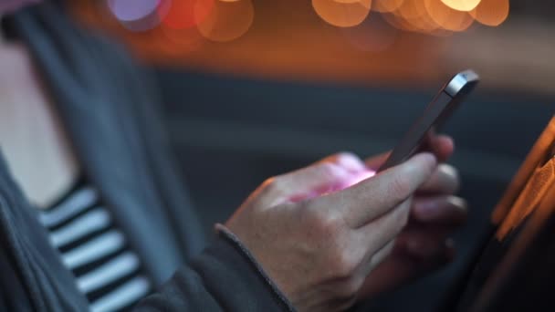 夜間の車内でのスマートフォンを使用して 携帯電話を手にした女性の選択的フォーカス低キー画像 — ストック動画