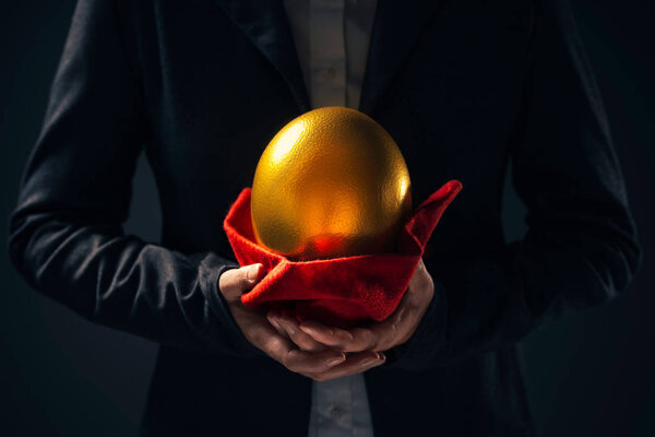 Large golden egg in hands of female business person