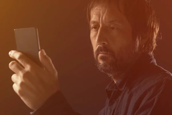 Hombre adulto mirando la pantalla del teléfono móvil —  Fotos de Stock