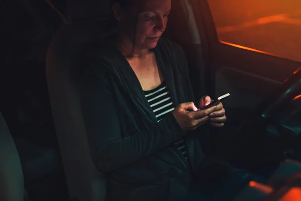 Donna che messaggia sul telefono cellulare in auto di notte — Foto Stock