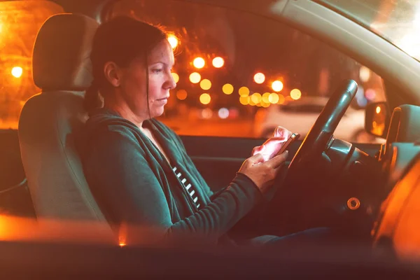 Donna che messaggia sul telefono cellulare in auto di notte — Foto Stock