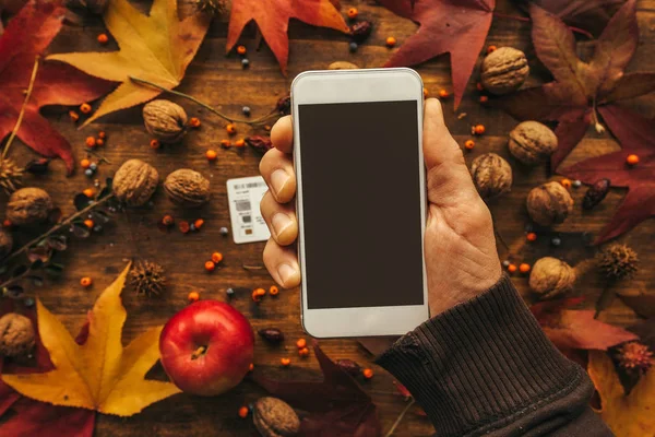 Mock up smartphone in hand with autumn decoration