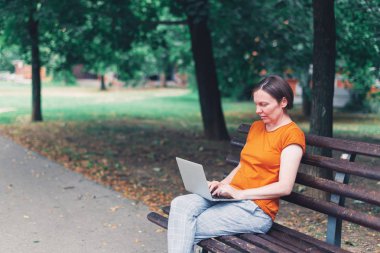 Park Bench üzerinde dizüstü bilgisayar kullanan kadın