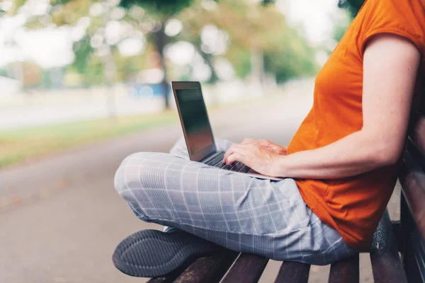 Mulher usando computador portátil no banco de parque — Fotografia de Stock