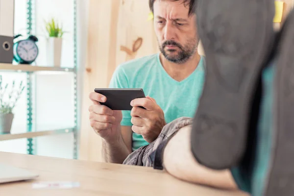 Freelancer playing mobile video game on smartphone in home offic