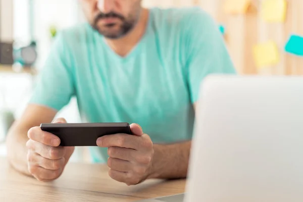 Freelancer jogando videogame móvel no smartphone em casa offic — Fotografia de Stock