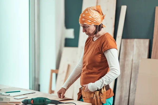 Charpentier féminin sérieux qui pense au projet — Photo