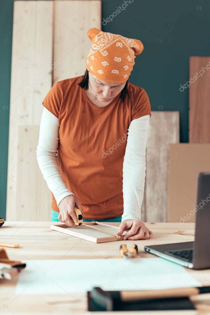 Female carpenter tape measuring picture frame in workshop