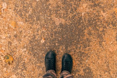 Ezilmiş kuru yapraklarla kaplı kaldırımda durmak